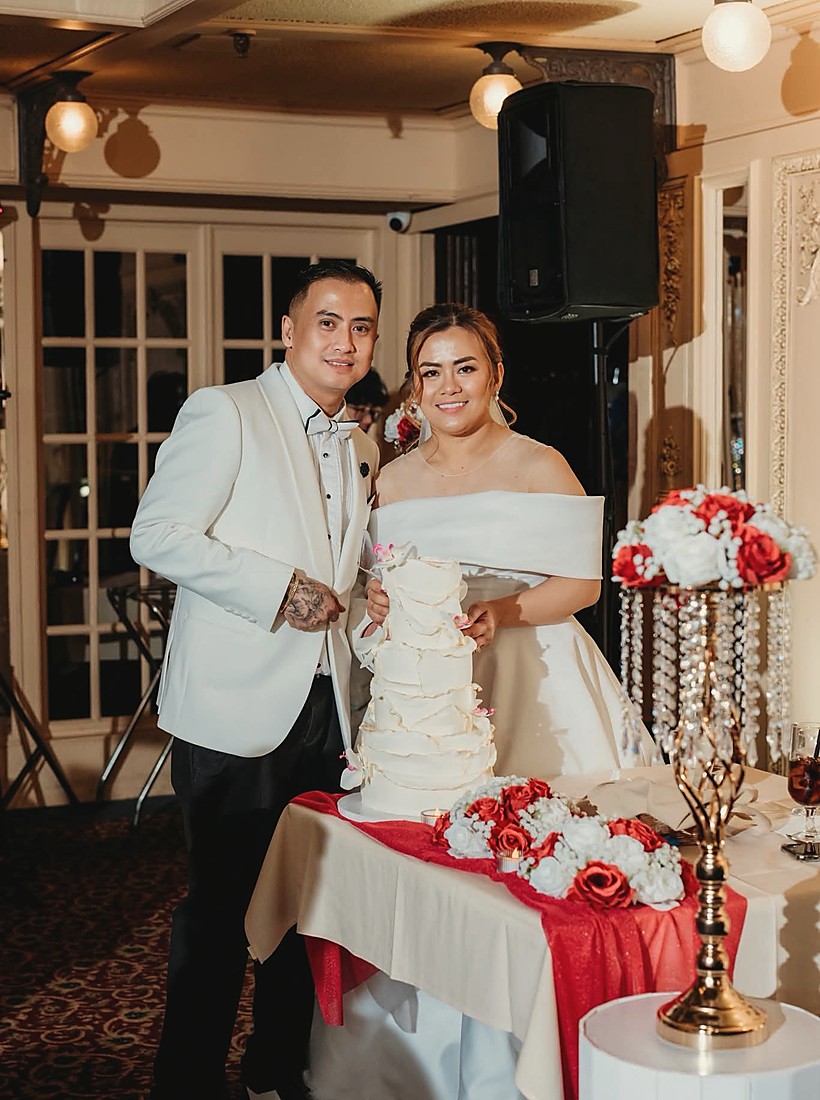 A white wedding cake with the words in every lifetime piped across the top tier