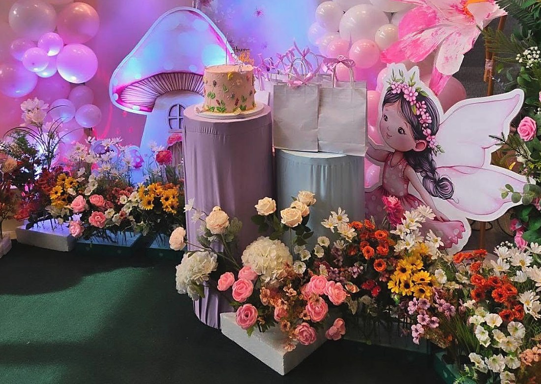 A pastel fairy themed first birthday setup with balloons and flowers
