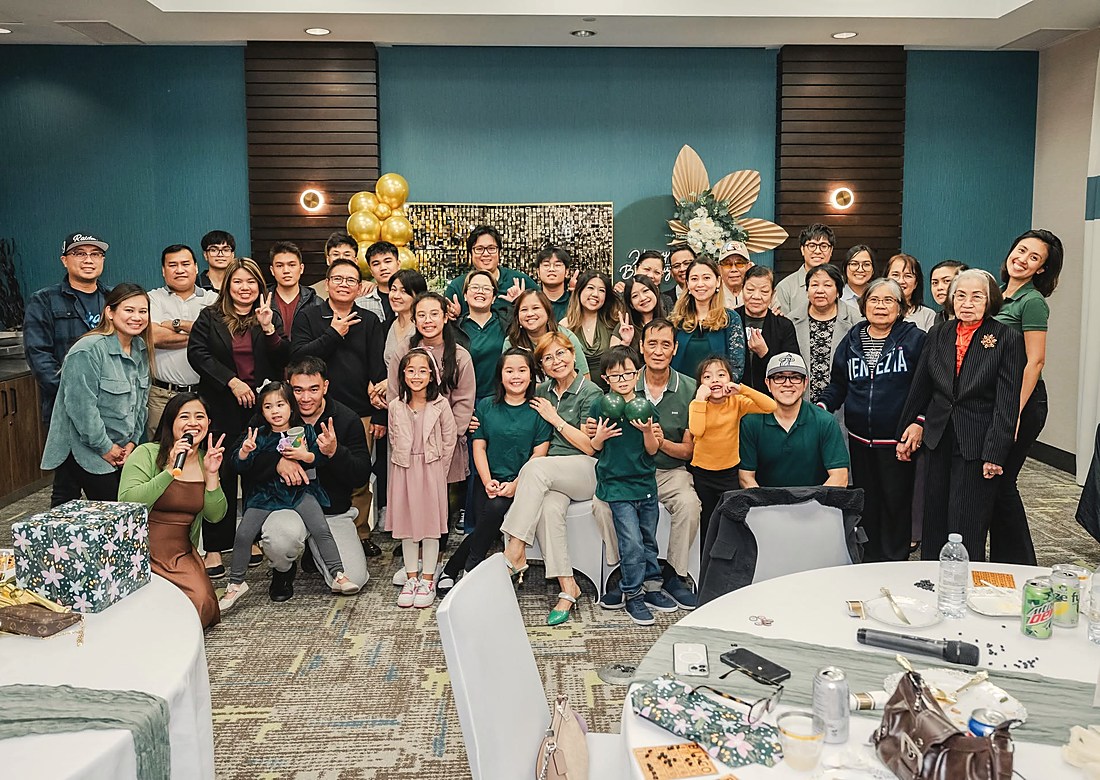 Family and friends gathered under a gold balloon arch