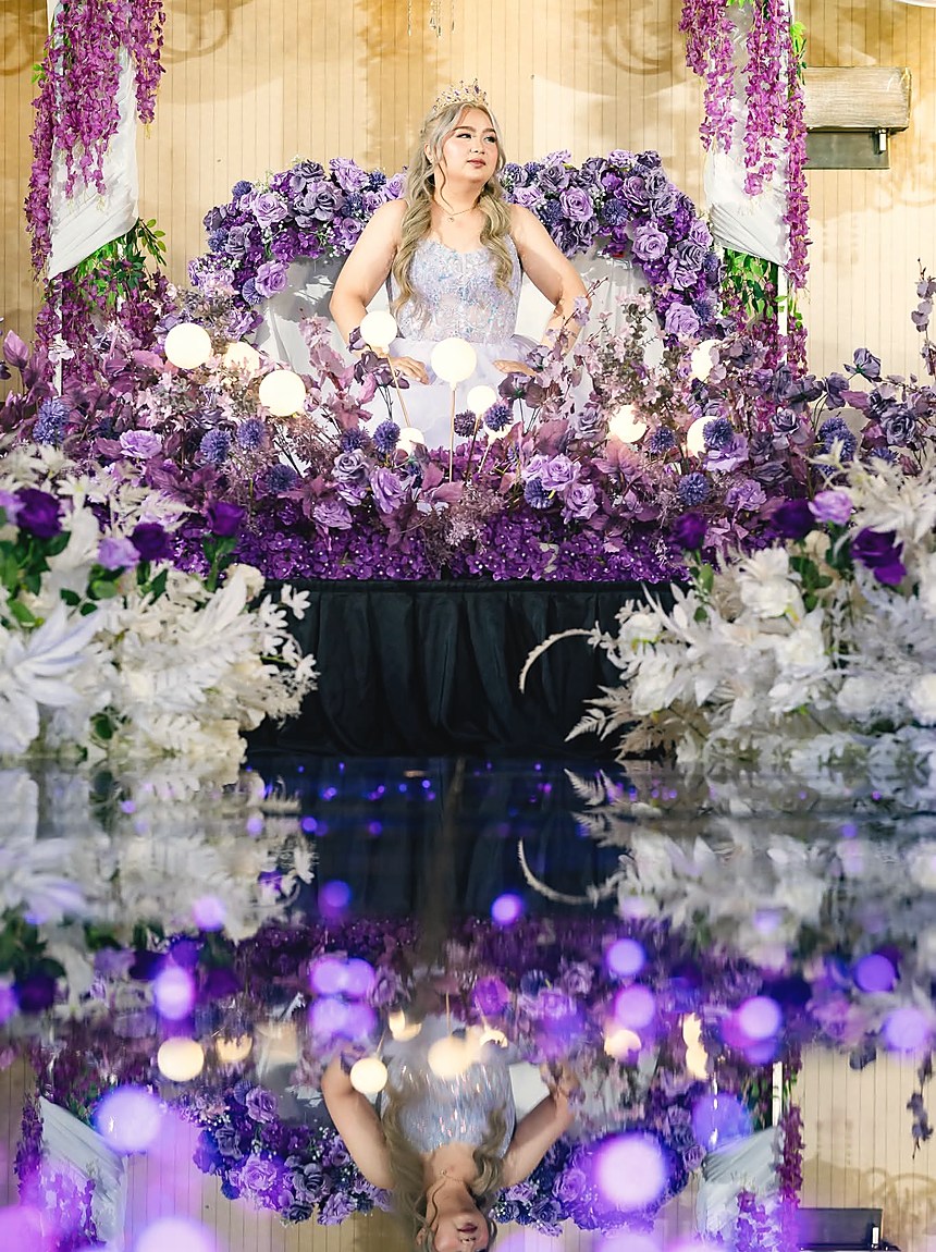 A mirrored stage banked with purple and white flowers