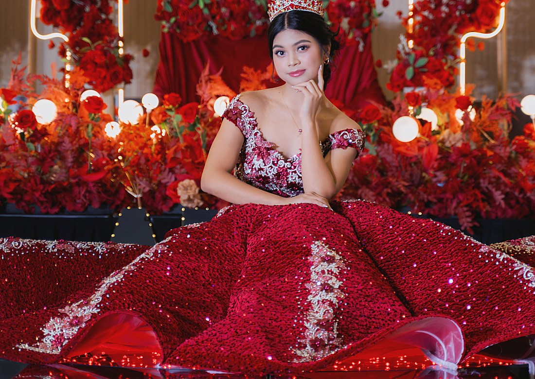 A red ball gown spread across a mirrored stage under warm lights