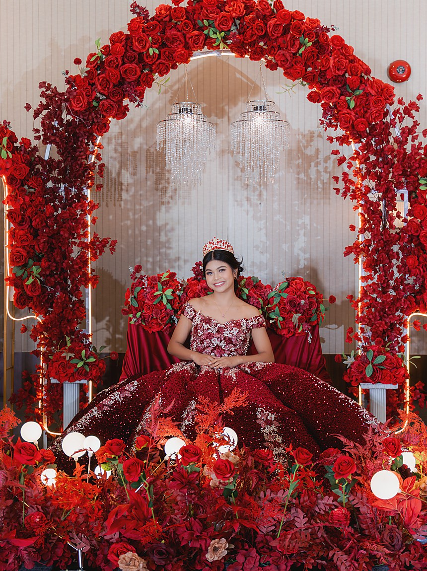 A debutante framed inside a tall arch of red flowers