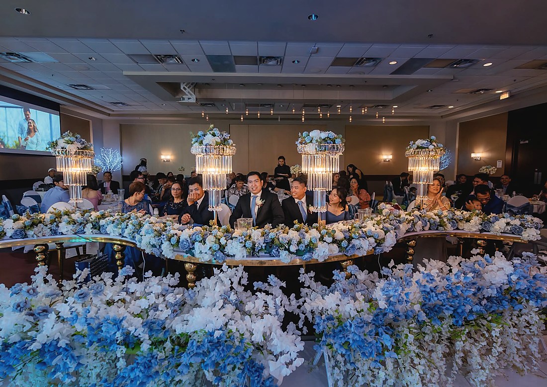 A full reception room seen across the flowers of the head table
