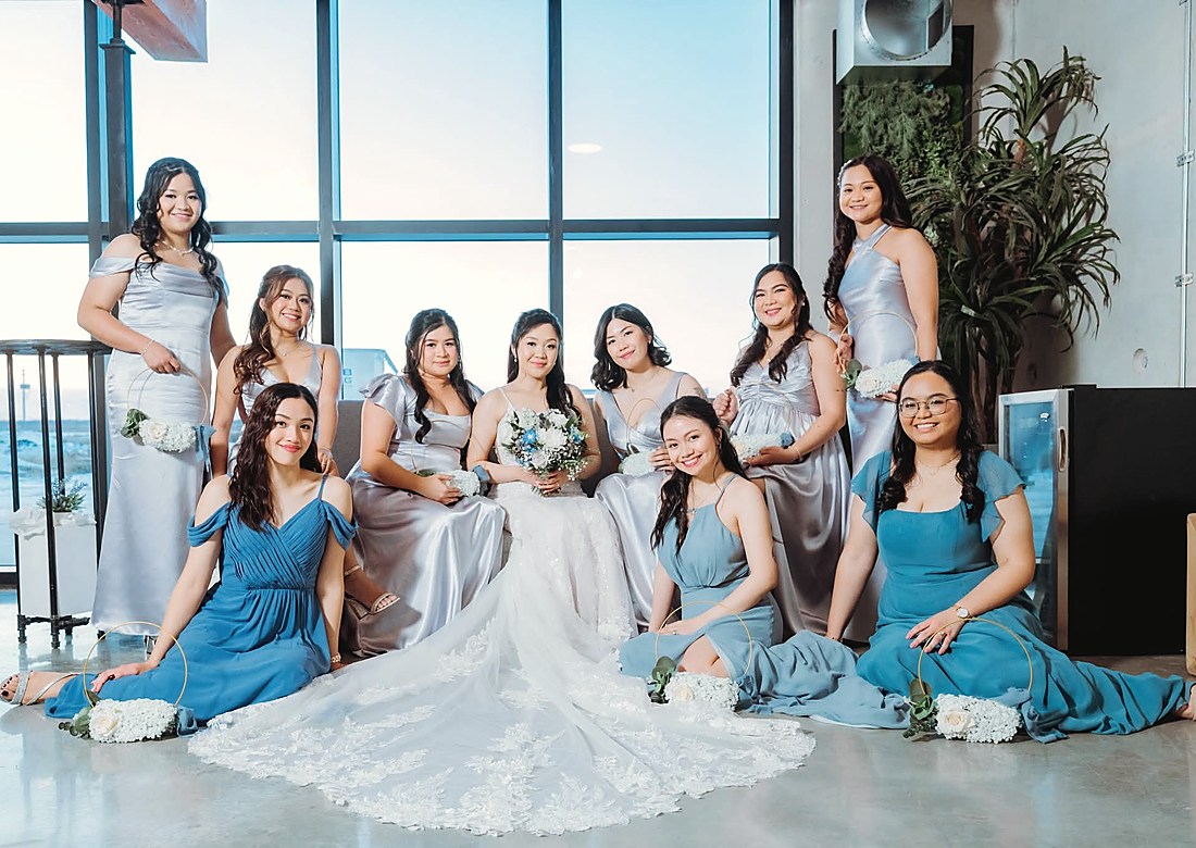 The bride seated with her bridesmaids in dusty blue gowns