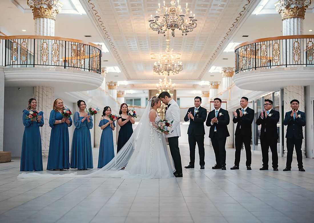 A couple embracing in an empty ballroom beneath a chandelier