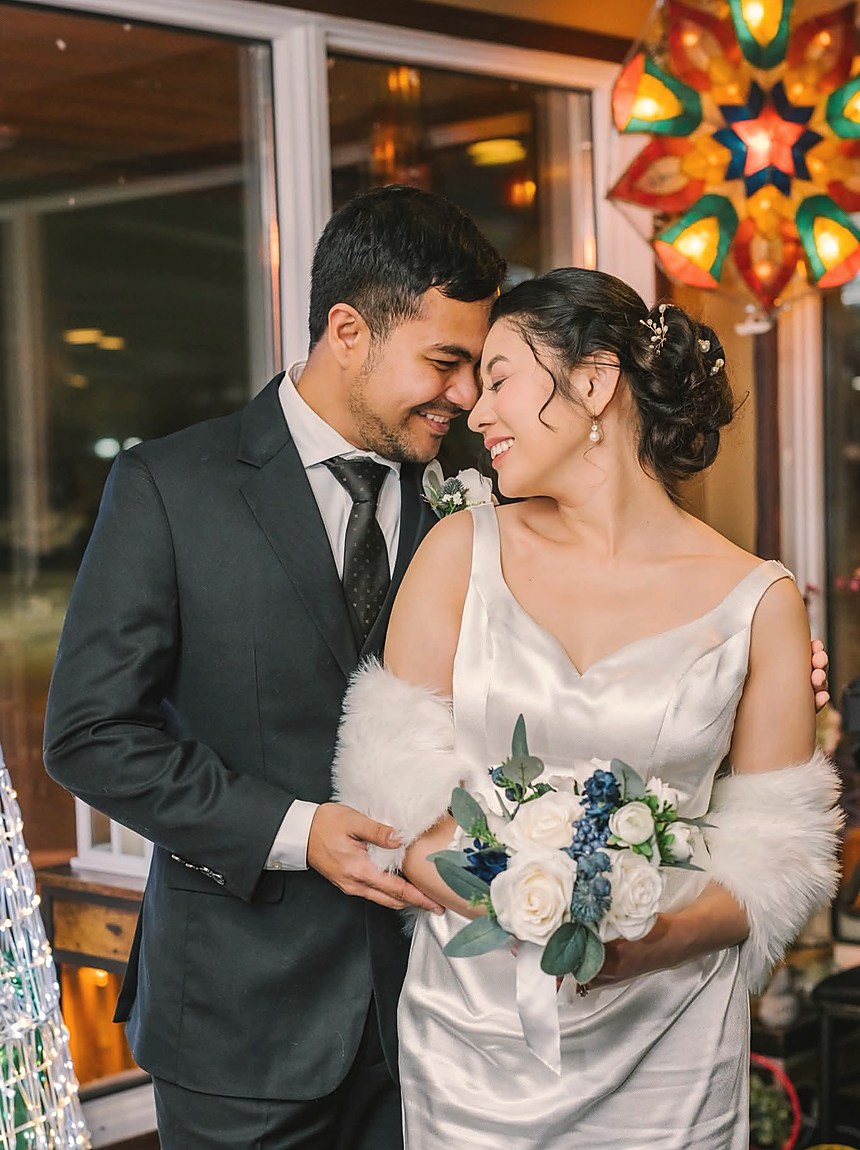 A couple standing close, the bride holding a winter bouquet