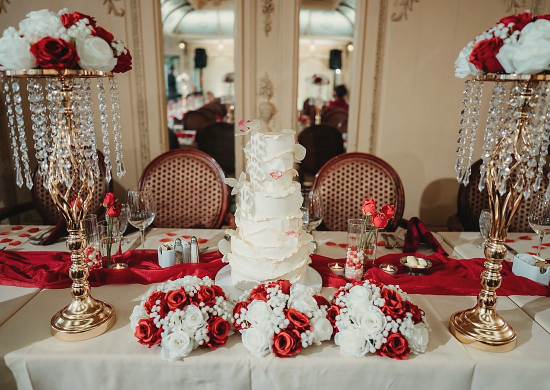 A reception table in red and white with a tiered cake behind it