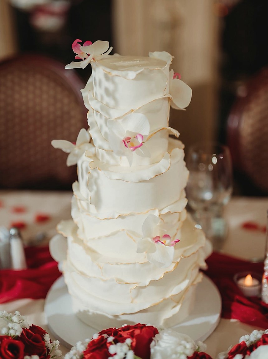 A tiered white wedding cake trimmed with orchids