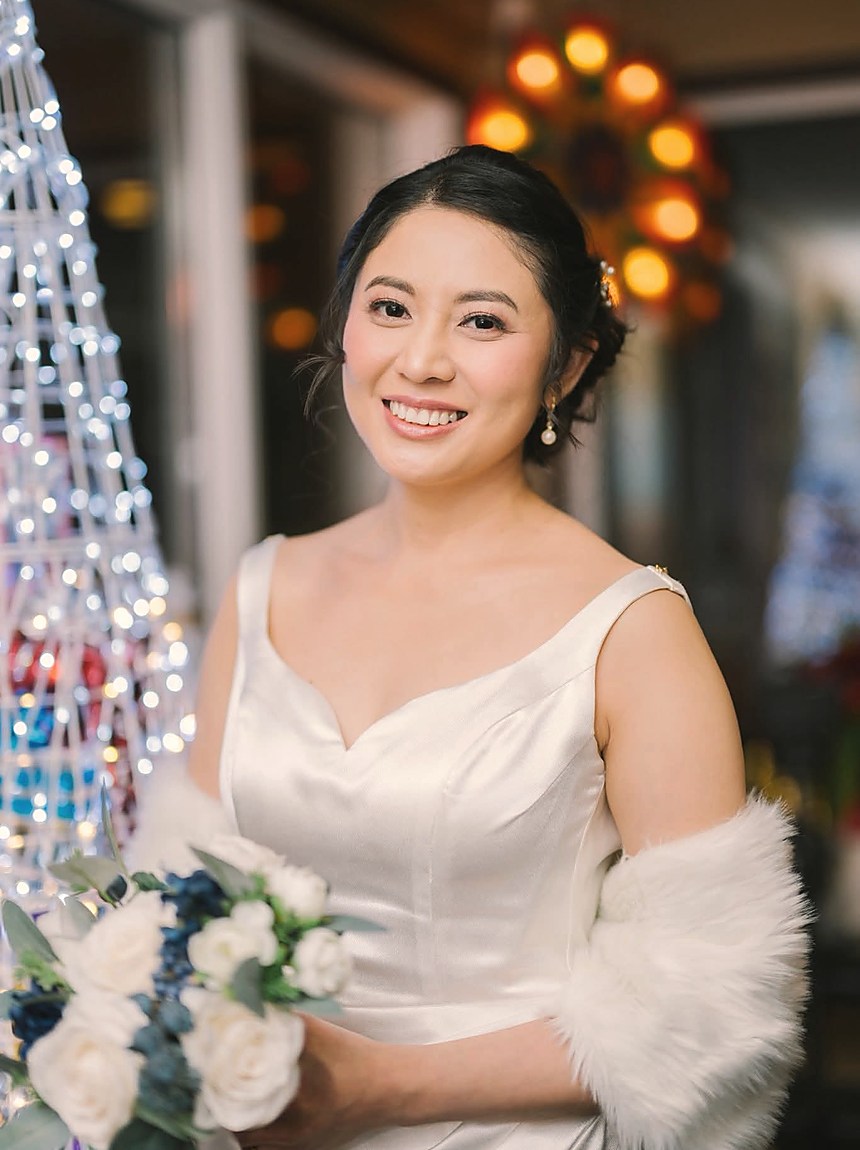 A bride in soft light holding her bouquet, string lights behind her