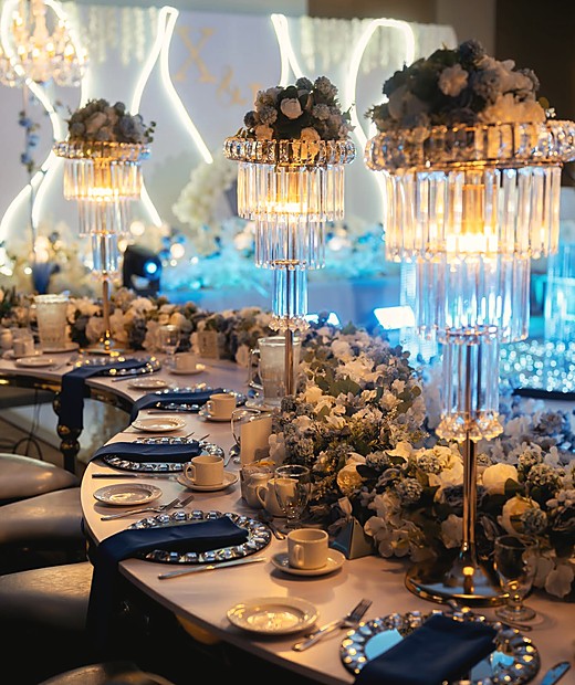Long banquet tables in cream and blue under lit crystal candelabra