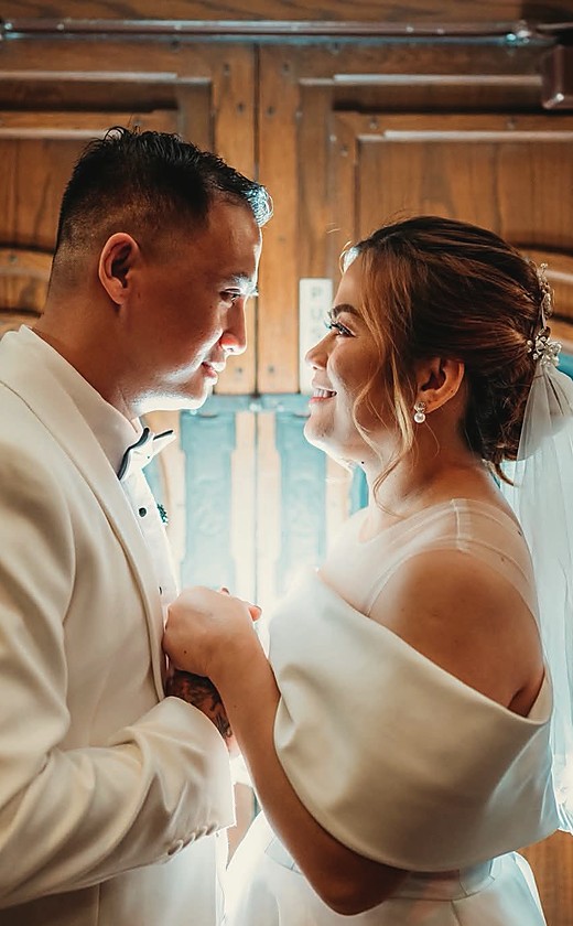 A couple looking at each other in front of an arched wooden door