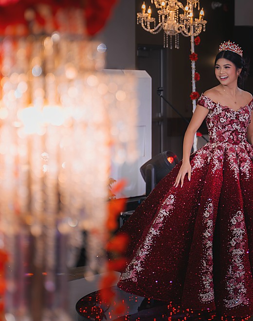 A debutante in red seen past the crystals of a lit chandelier