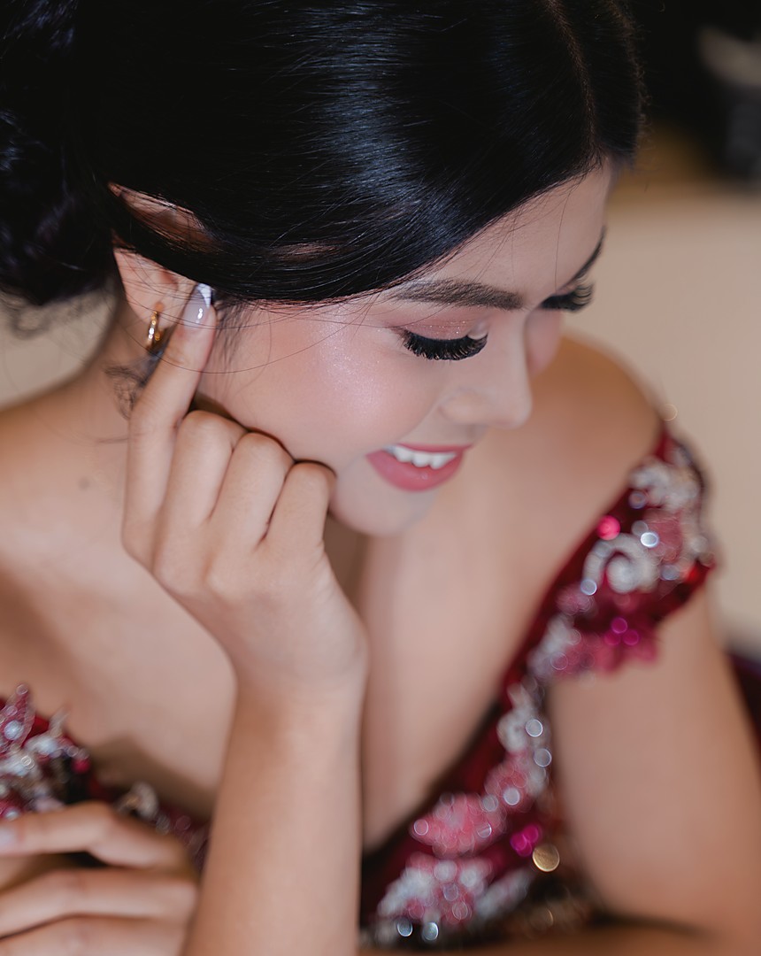 A debutante in a beaded red gown resting her chin on her hand